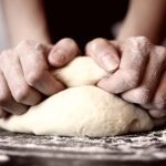 Image of hands kneading pizza dough.