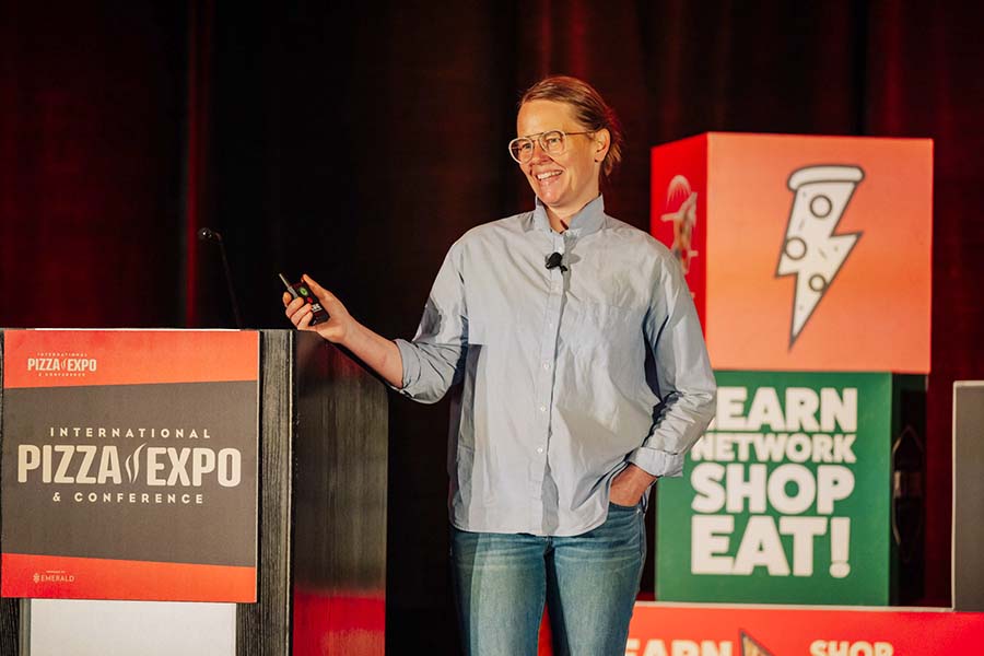 Image of Sarah Minnick of Lovely's Fifty Fifty giving keynote address at Pizza Expo 2025.