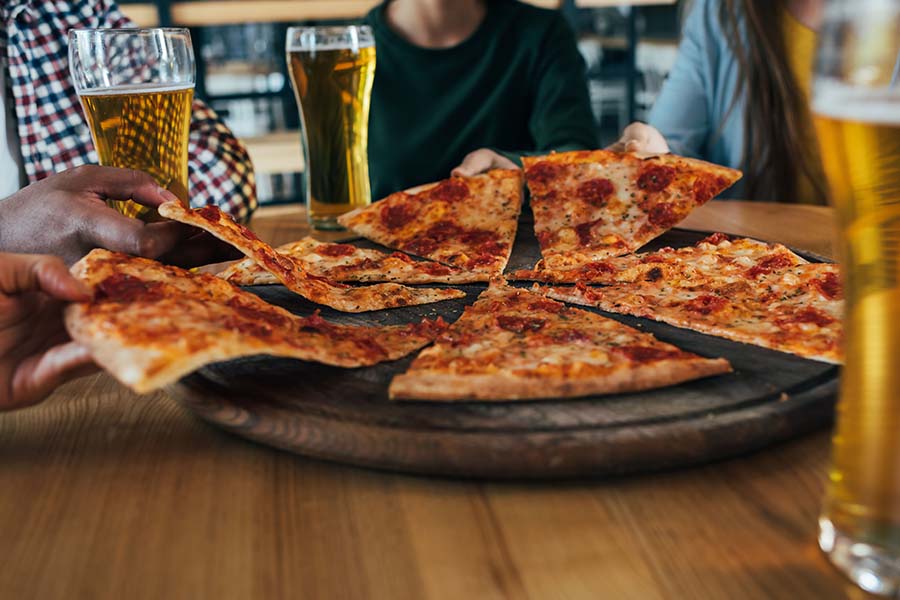 Image of group sharing pizza and beer.