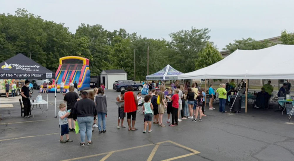 Image of families waiting in line for free "Heavenly Haircuts" sponsored by Heavenly Pizza.