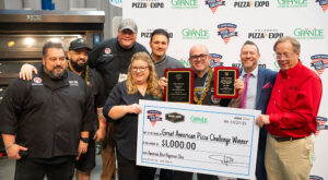Image of Chris Battiste claiming the "big check" for winning America's Best Pepperoni Slice at Pizza Expo Columbus.
