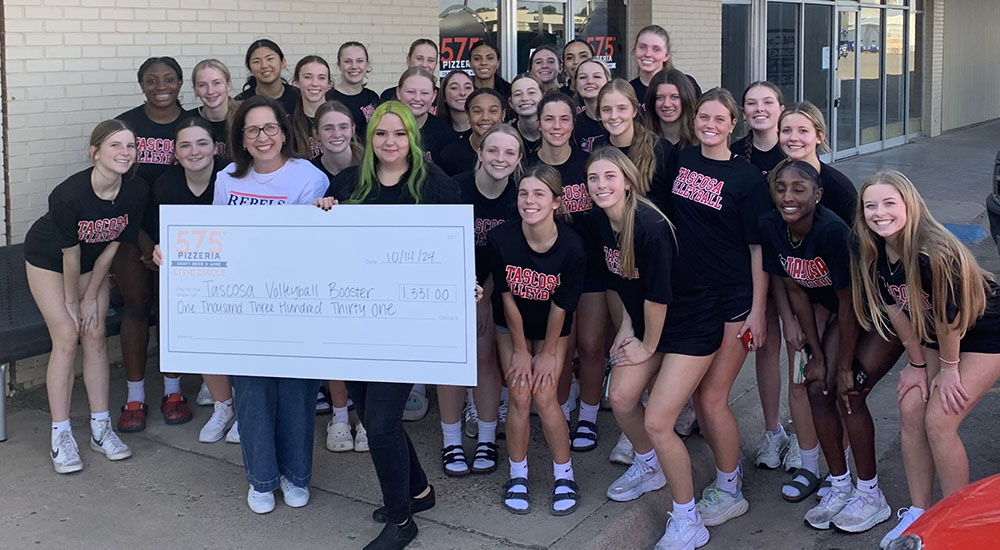 Image of Tacosa High School volleyball team holding fundraising check outside 575 Pizzeria in Amarillo, Texas.