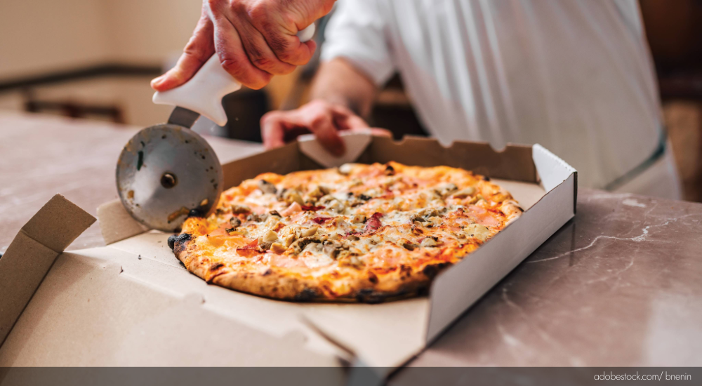Image of pizza being boxed for delivery.