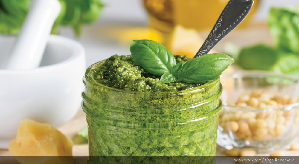 Image of pesto in a jar, topped with basil.